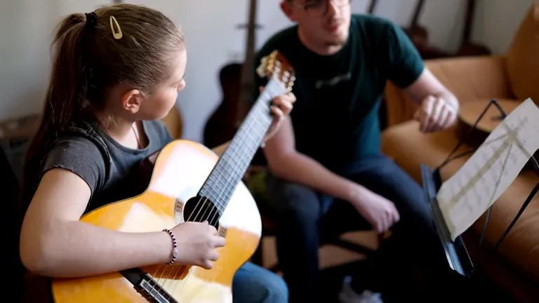 Child learning guitar during a music lesson to develop creativity and cognitive skills