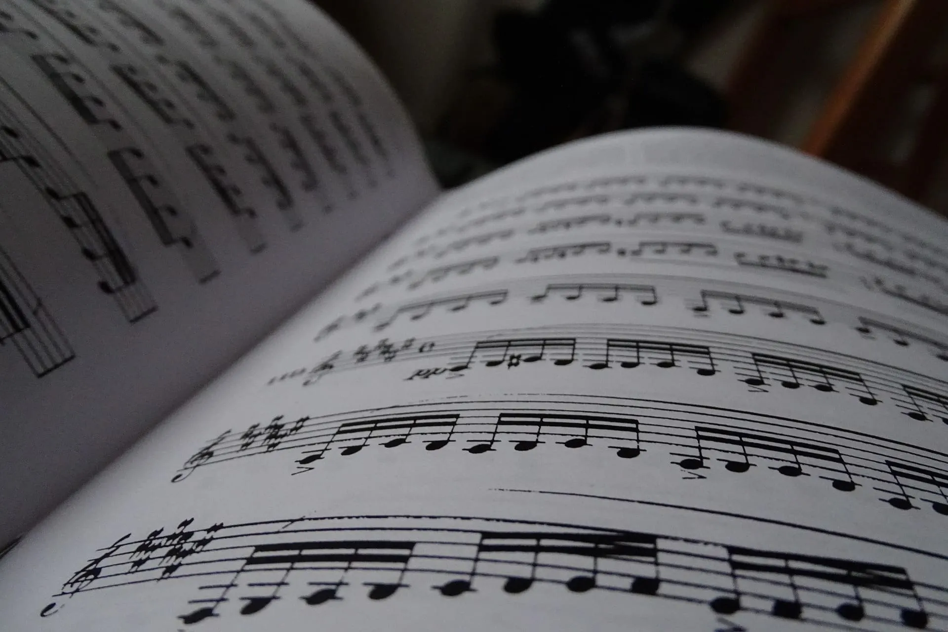 Close-up of an open sheet music book with musical notes and notation in focus.